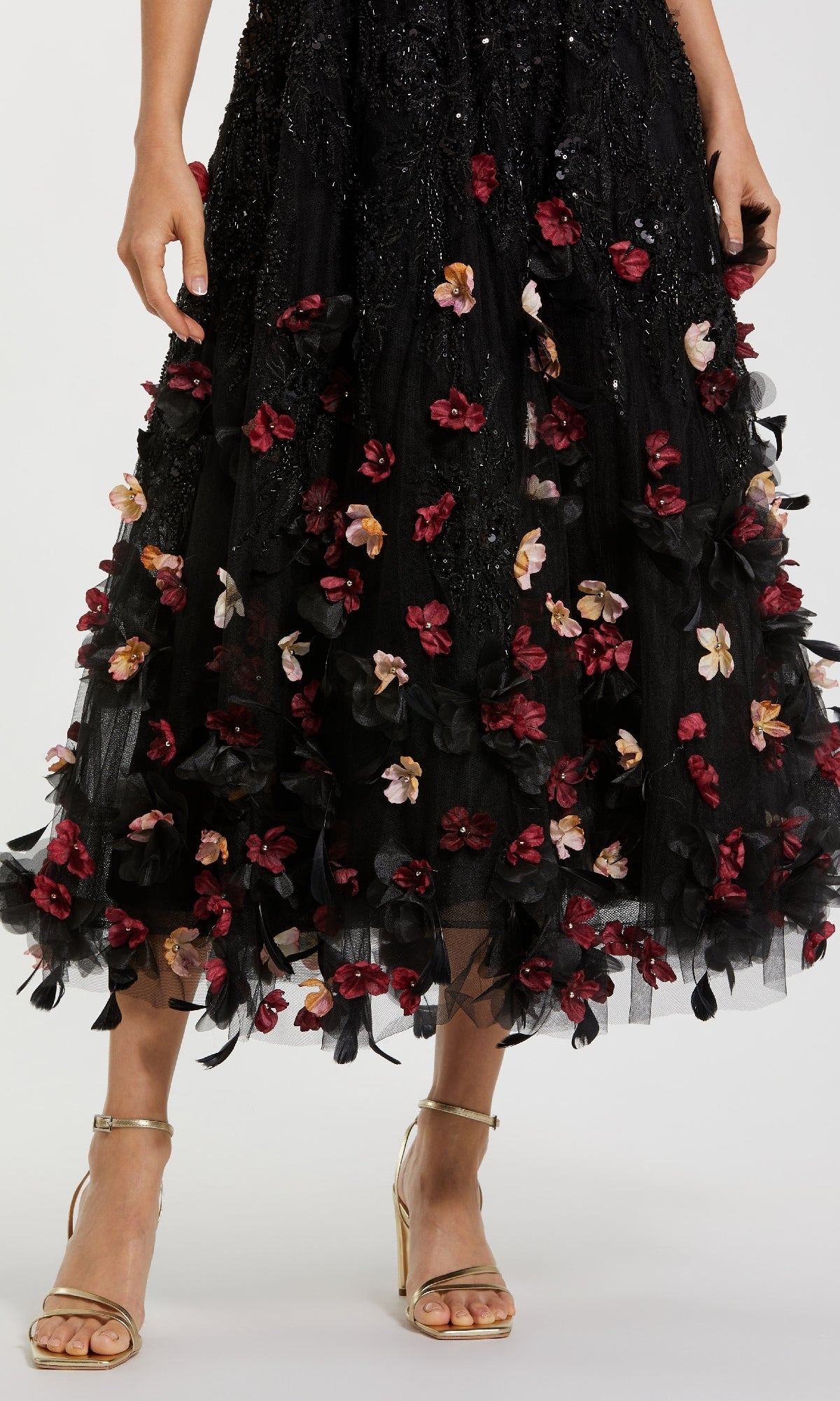 A person wearing the Mac Duggal 21085 A-Line Wedding Guest Dress, a black midi with red and pink floral appliques, paired with gold strappy heels.